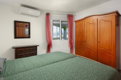 a bedroom with a green bed and a wooden cabinet at Apartamento junto a la playa A11 in Torrox