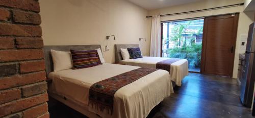 two beds in a room with a brick wall at Casa de la Ballena in Sayulita