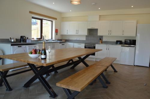 a kitchen with a wooden table and two benches at The Farmhouse at Williamscraig Holiday Cottages in Linlithgow