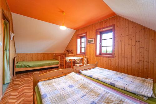 een slaapkamer met 2 bedden, een tafel en een raam bij Penzion U Zatoky in Horní Planá