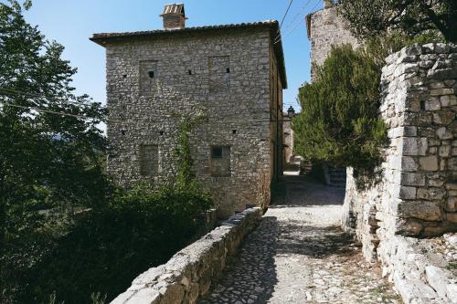 an old stone building with a stone wall next to a street at Albergo Diffuso Crispolti in Labro Rieti