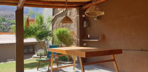 a wooden table and chairs in front of a house at La Casa de los Molles in Tilcara