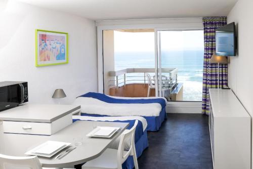 a hotel room with two beds and a desk and a window at Résidence Victoria Surf in Biarritz
