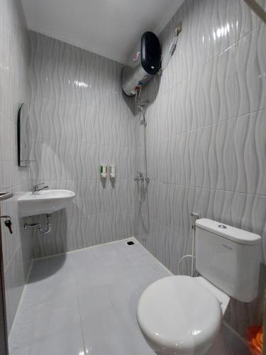 La salle de bains est pourvue de toilettes et d'un lavabo. dans l'établissement Harmony Inn Belitung - City Hotel, à Tanjung Pandan