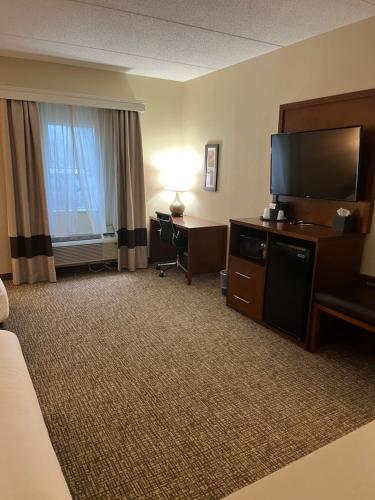 a hotel room with a bed and a television and a desk at Wingate by Wyndham Pittsburgh West Mifflin in West Mifflin