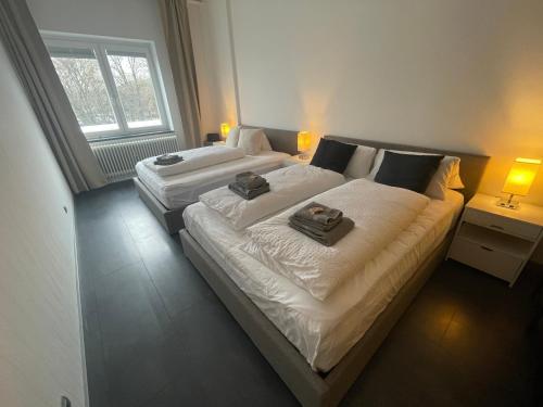 two beds in a hotel room with towels on them at TruRetreats Design Loft I Riesige Küche I Wallbox I 65z SmartTV I 150qm in Hamburg