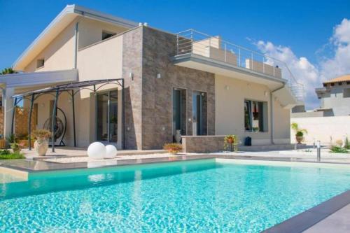 a villa with a swimming pool in front of a house at Villa Sele Fontanebianche - pool in Fontane Bianche