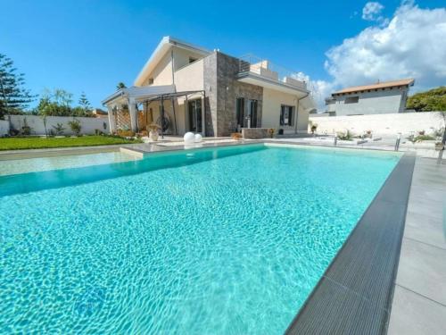 a swimming pool in front of a house at Villa Sele Fontanebianche - pool in Fontane Bianche