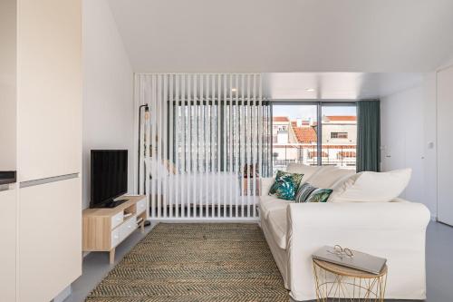 a white living room with a white couch and a tv at Succeed Campo Pequeno Apartments in Lisbon