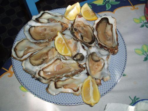 a plate of oysters with lemon slices on a table at Apartments Butinar Pri Kapitanu in Ankaran