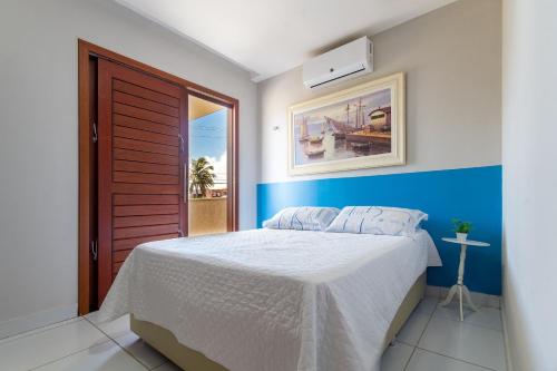 a bedroom with a bed with a blue accent wall at Incrível casa na Praia de Camurupim por Carpediem in Nísia Floresta