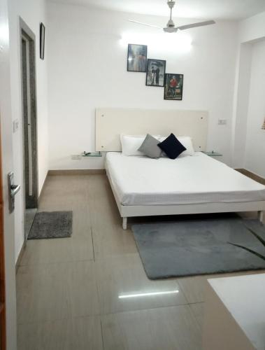 een witte slaapkamer met een bed en een vloer bij House 44 1BHK in Greater Noida