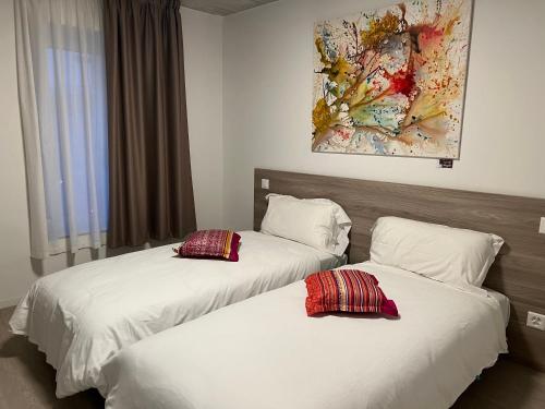 Regina Bed & Breakfast في اجنو: سريرين في غرفة الفندق مع شراشف بيضاء ومخدات حمراء