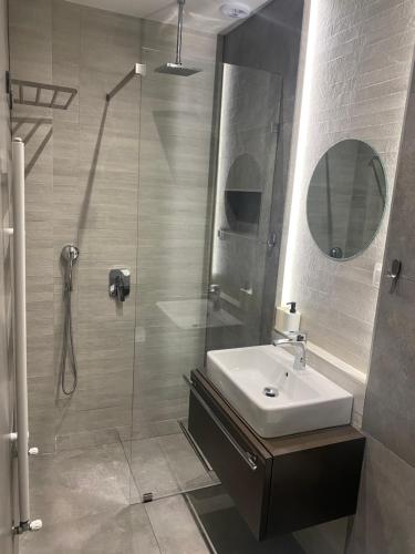 a bathroom with a sink and a shower with a mirror at Central cozy apartment with garden in Alexandroupoli