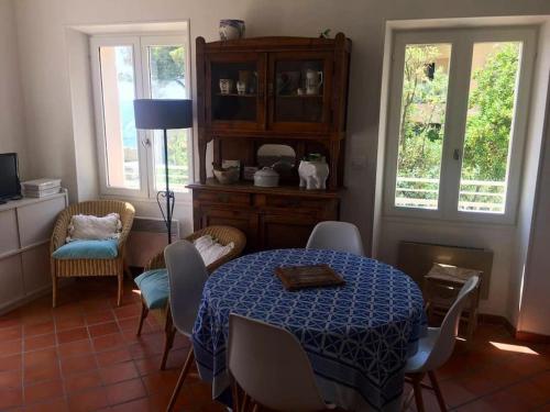 une salle à manger avec une table, des chaises et des fenêtres dans l'établissement L’Aiguade, appartement d'exception à Cassis, à Cassis