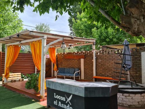 a wooden pergola with a bench and an umbrella at Alojamiento Quincho Pascual in Las Compuertas
