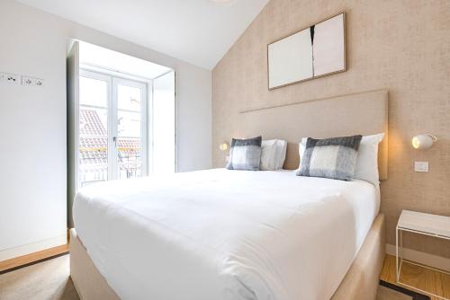 a large white bed in a room with a window at Ando Living - Douradores House in Lisbon