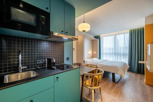 eine Küche mit einem Waschbecken und ein Bett in einem Zimmer in der Unterkunft Aparthotel Adagio access Hamburg in Hamburg