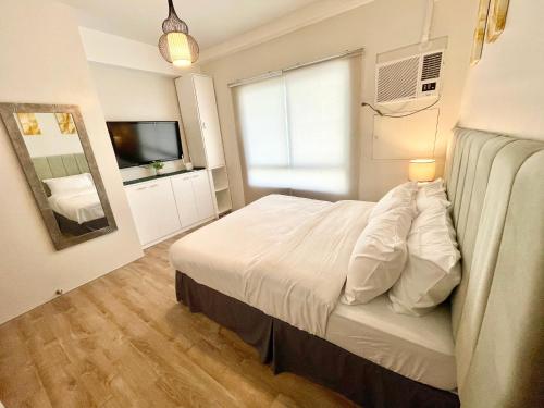 - une chambre avec un lit blanc et un miroir dans l'établissement One bedroom Condo Suite in Bacolod City, à Bacolod