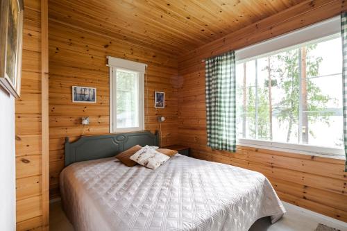 een slaapkamer met een bed in een houten hut bij Kujanpää | Paajoen Vuokramökit in Himos