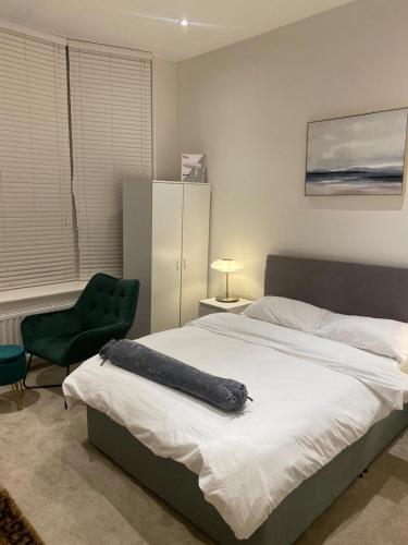 a bedroom with a large bed and a green chair at I&J Suites in Woolwich