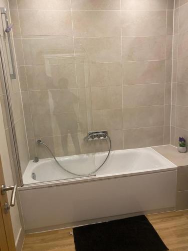 a bathroom with a bath tub with a shower at I&J Suites in Woolwich