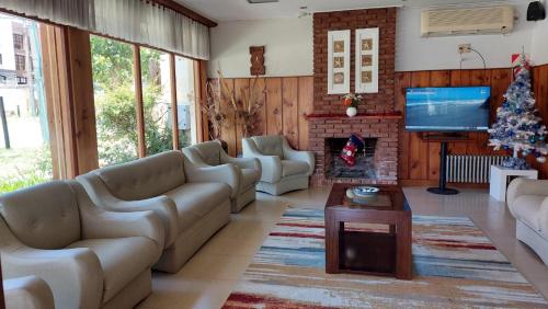 sala de estar con sofás, TV y chimenea en Hotel Riviera en Villa Gesell