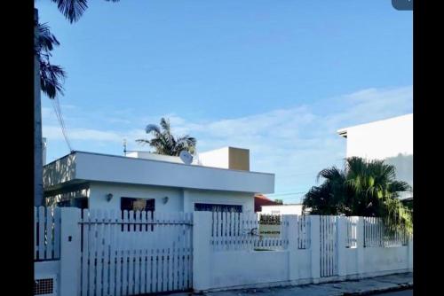 una cerca blanca frente a una casa blanca en Residencial Casa da Vila apto 3, en Imbituba
