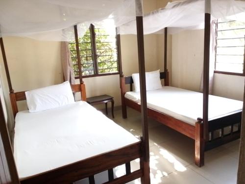 a room with three bunk beds and two windows at Cingaki Hotel in Mombasa