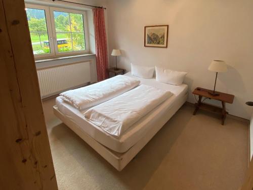 a bedroom with a white bed and a window at Chalet Jochpass Ferienwohnungen by HOTEL LANIG - Ferienwohnungen mit Zugang zum WellnessSpa im Hotel Lanig in Bad Hindelang