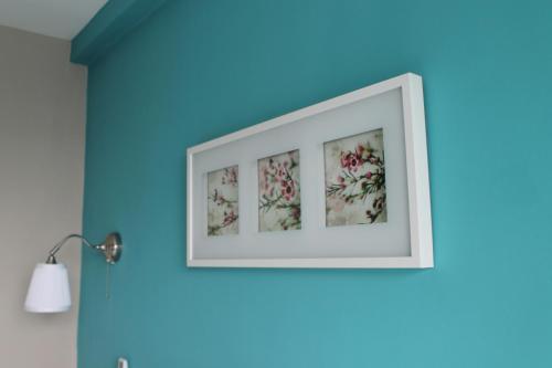 a framed picture of flowers on a blue wall at V-Ocean Palace in Hat Yai