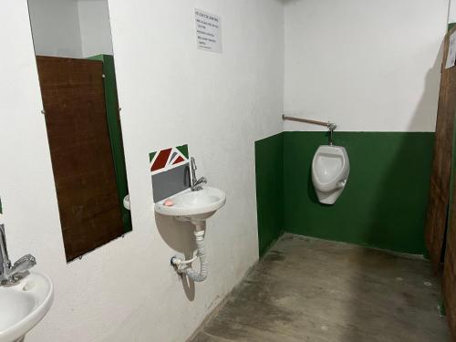 a bathroom with a sink and a urinal and a toilet at Aluguel de mini quartos e barracas no Perequê-açu de frente para o mar numero 1125 in Ubatuba
