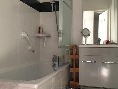 une salle de bain blanche avec une baignoire et un miroir dans l'établissement Appartement familial près de la plage avec parking et balcon verdoyant - FR-1-482-49, à Fort-Mahon-Plage