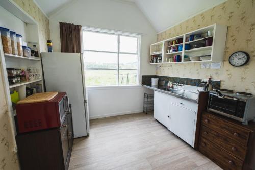 a kitchen with a refrigerator and a sink and a window at Cliff Top Cottage in Ohingaiti