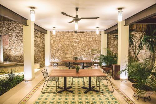 Habitación con mesas, sillas y pared de piedra. en TreeHouse Boutique Hotel, an adults only boutique hotel en Mérida