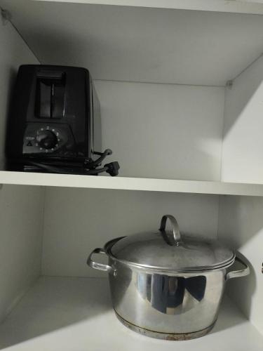 a pot on a shelf next to a toaster oven at Cómodo dpto full equipo 2 hab, seguridad y parqueo privado in Guayaquil