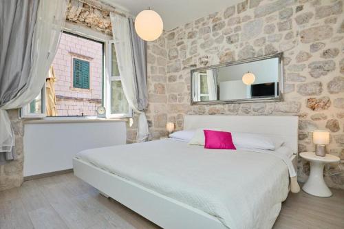 a bedroom with a white bed and a stone wall at Festa Apartments in Dubrovnik