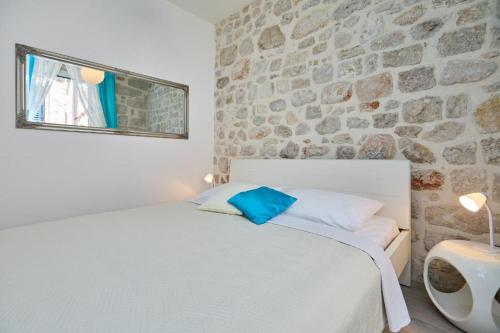 a bedroom with a white bed and a stone wall at Festa Apartments & Rooms in Dubrovnik