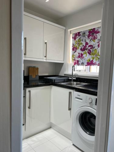 a white kitchen with a washing machine and a window at Home Away in Wigan
