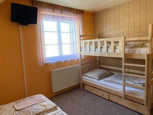 a bedroom with two bunk beds and a window at Penzion U Horejšů, Zadov - Churáňov in Stachy