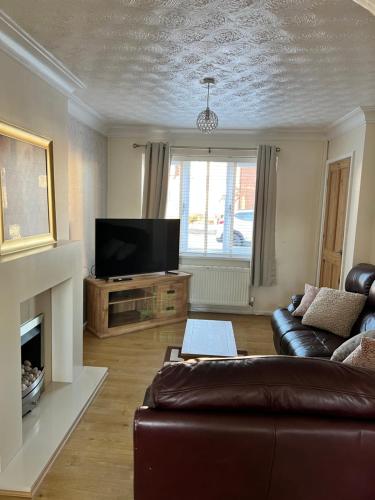 een woonkamer met een bank en een flatscreen-tv bij Home Away in Wigan