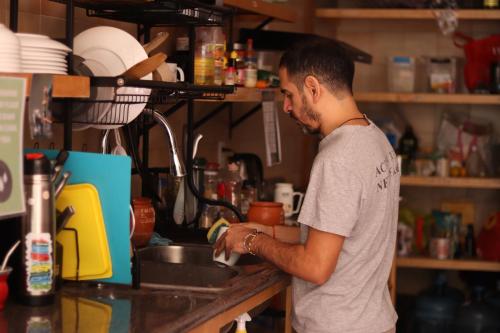 a man washing his dishes in a kitchen sink at Leveli Coliving in Guadalajara