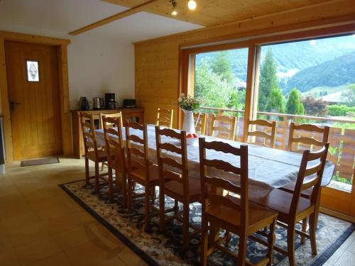 une salle à manger avec une table et des chaises et une grande fenêtre dans l'établissement Chalet Belle Folie, à Saint-Jean-dʼAulps