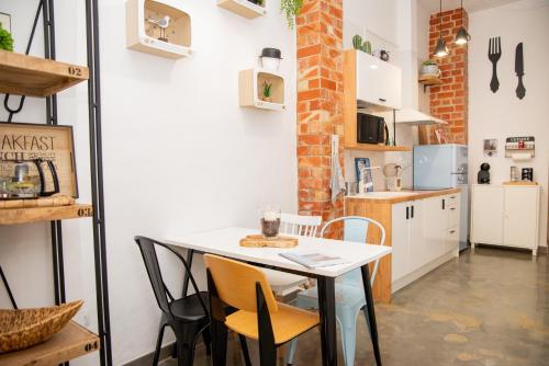 uma pequena cozinha com uma mesa branca e cadeiras em Maná Loft Apartamento original en el centro de Alicante em Alicante