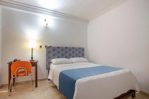 a bedroom with a bed and a table and a chair at Hotel Ayenda Boutique Real Capital Monteria in Montería
