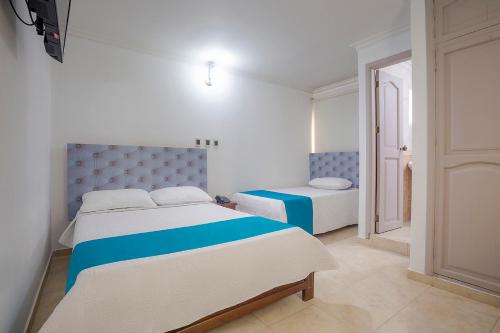 a white and blue bedroom with two beds at Hotel Ayenda Boutique Real Capital Monteria in Montería
