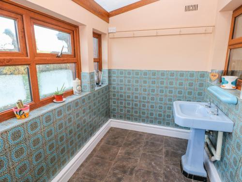 a bathroom with blue tiled walls and a sink at Pant Teg Farm in Kidwelly