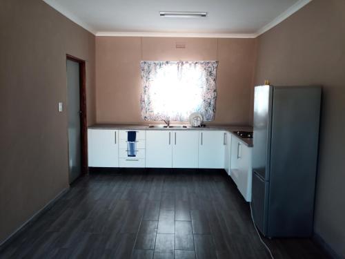 a kitchen with a refrigerator and a window at NAMU Apartments in Katima Mulilo