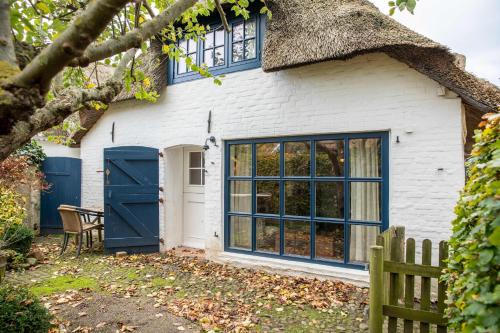 a cottage with a thatched roof and a blue door at Ferienhaus Strandgut in Oevenum