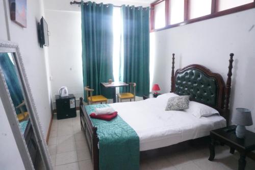 um quarto com uma cama com uma cortina verde em Happy Ours Guesthouse em Curepipe